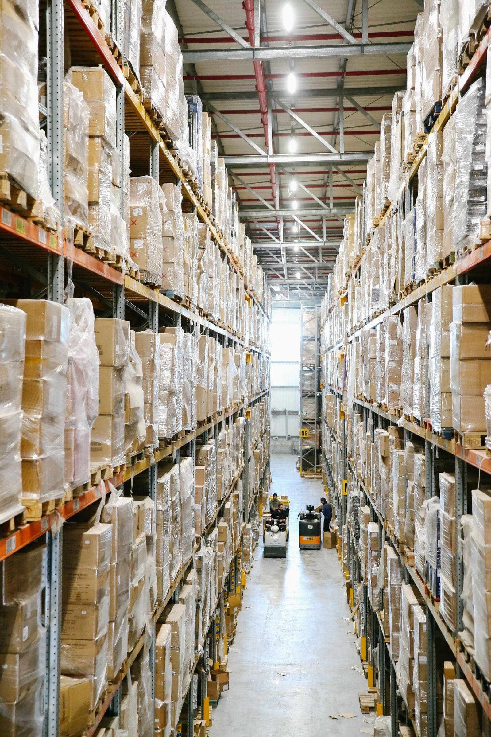 A long warehouse aisle lined with shelves of boxed stock