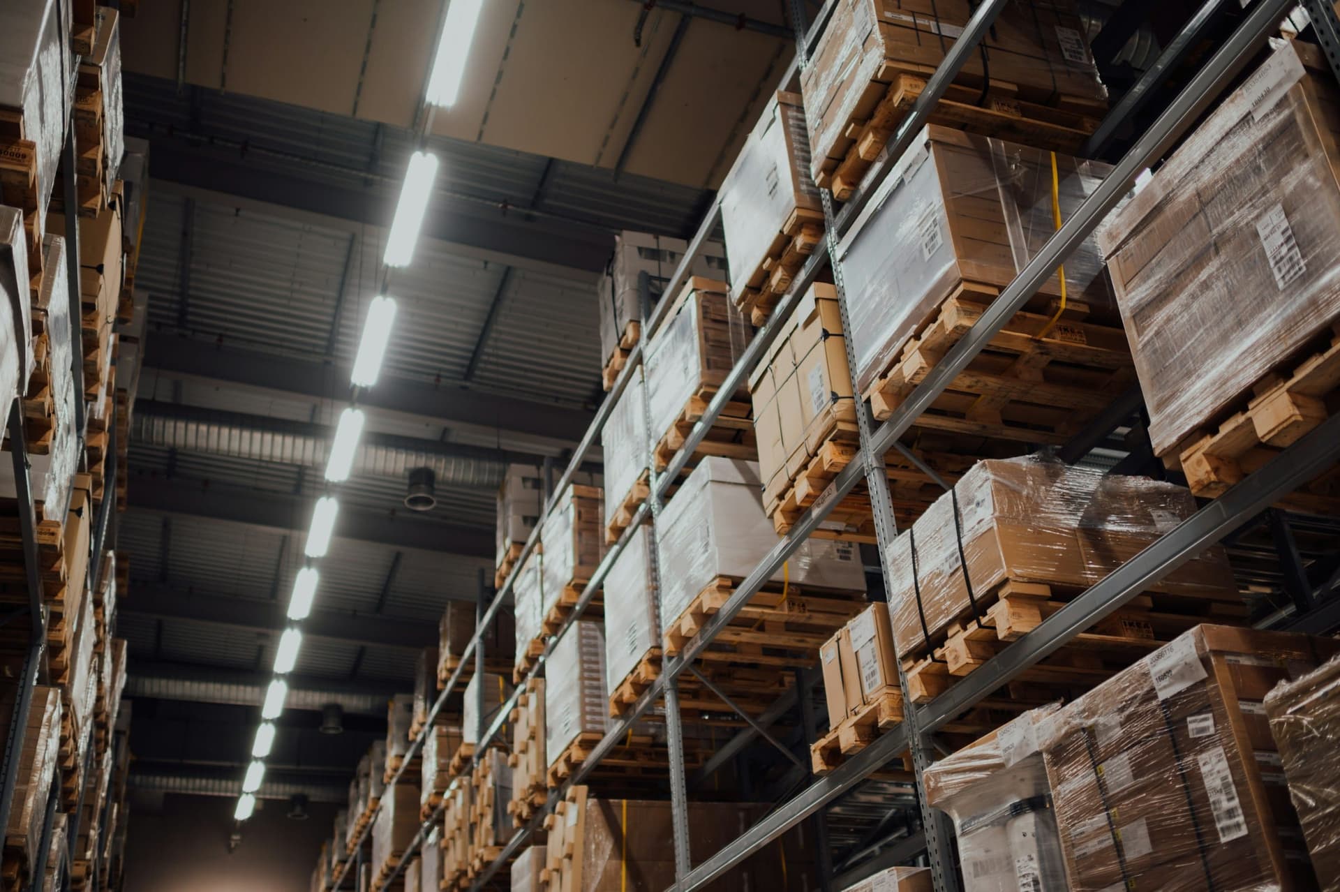 Tall warehouse racking stacked with boxed, shrink-wrapped pallets