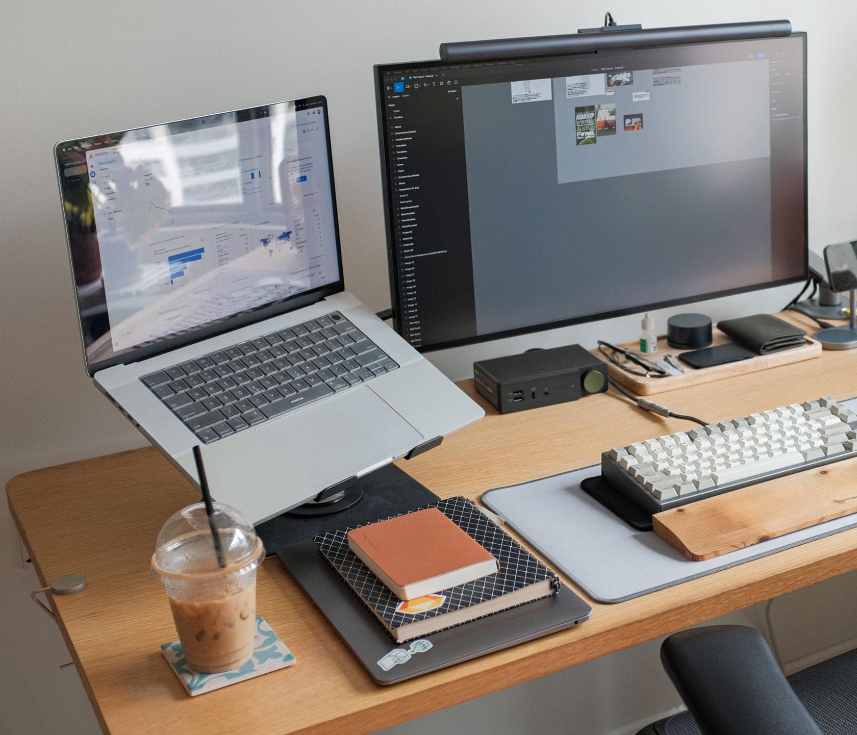 A desk with a laptop on a stand, a monitor with a light bar, a keyboard and a mouse